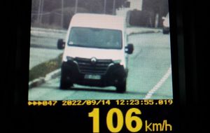 Widok z kamery urządzenia do pomiaru prędkości. Widoczny biały samochód dostawczy. Na dole kadru wyświetlona prędkość 106 km/h