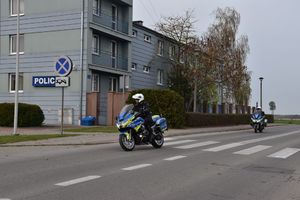 Dwaj policjanci  jadą na motocyklach  jeden za drugim po ulicy Klonowej w Oleśnie w tle budynek komendy.