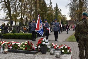 Poczet sztandarowy złożony z trzech policjantów oddaje honory pod Pomnikiem Lotników Polskich.