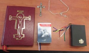 Na stole leża zabezpieczone przez policjantów skradzione przedmioty: Ewangeliarz, Pismo Święte, krzyż lektorski, różaniec.