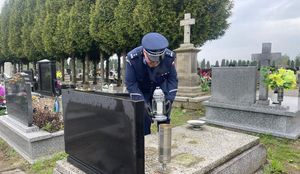 Zastępca Komendanta Powiatowego Policji w Oleśnie młodszy inspektor Waldemar Popczyk składa znicz na płycie nagrobka  rodziny jasieniów na cmentarzu w Przystajni.
