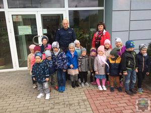 Grupa przedszkolaków z umundurowanym  policjantem stoi przed wejściem do KPP w Oleśnie.