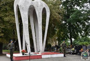 Pomnik Lotników Polskich na oleskim cmentarzu komunalnym przy nim warta honorowa złożona z dwóch żołnierzy