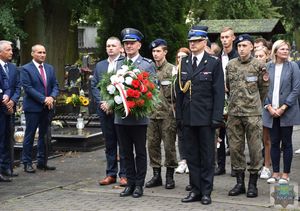 Komendant Powiatowy Policji w Oleśnie i przedstawiciel Państwowej Straży Pożarnej w Oleśnie oczekują na złożenie biało-czerwonej wiązanki kwiatów przed pomnikiem Lotników Polskich